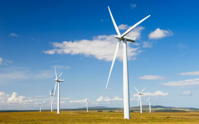 Several wind turbines pictured, on land with a blue sky and some clouds in the background.