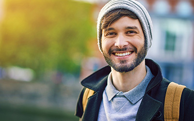 A man standing outdoors, smiling directly at the camera