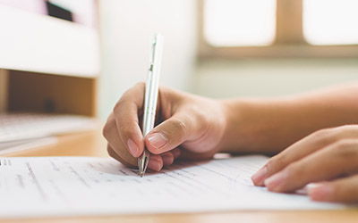 A hand holding a pen on a sheet of paper