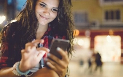 A smiling woman, holding a mobile phone