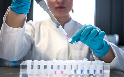 A female scientist pipetting coloured chemicals into a tube