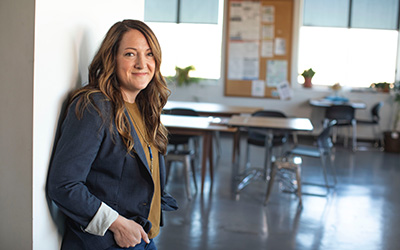 Smiling female standing in a room with her back against a wall