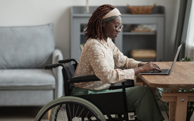 A woman in a wheelchair using her laptop at home