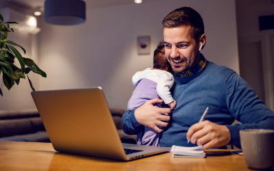 A man studting whilst holding a newborn baby