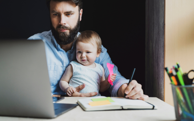 A man with his baby on his lap, working on a laptop