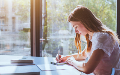 A student seated at a table writing notes