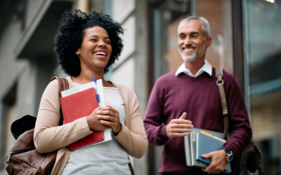 Happy adult students laughing in front of university library. iStock/Drazen Zigic