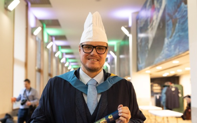 Graduate Graeme Gunn wearing chef hat and graduate robes - photo by Kathryn Tuckerman