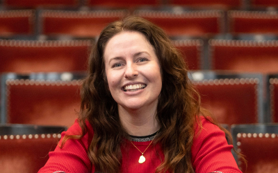 Katie Palmer sitting on a seat in a theatre auditorium 