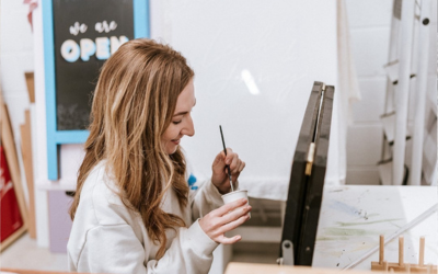 OU in Scotland student and entrepreneur Megan, painting at an easel 