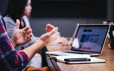 People sitting at a table with laptops having a meeting