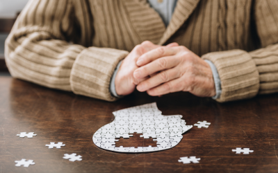 A person sitting in front of a jigsaw puzzle of a human head in profile