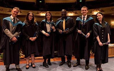 OU graduates pictured in their gowns on the stage on graduation day