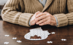 A person sitting in front of a jigsaw puzzle of a human head in profile