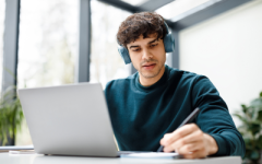 A student studying with his laptop, listening to a lecture
