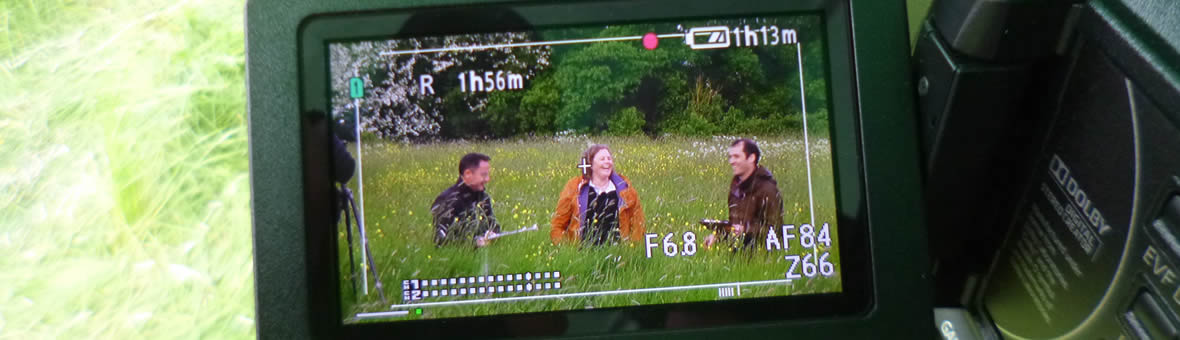 Study with us - camera viewfinder showing academics laughing as they work in a field
