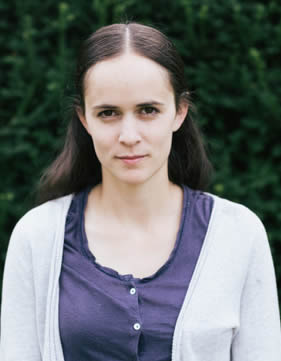 Bethan Parkes - a woman stands in front of green folage.