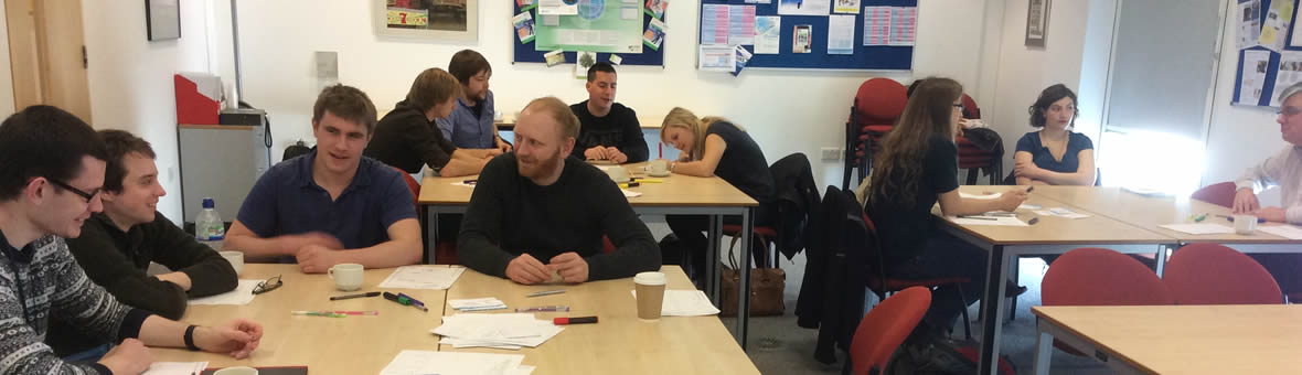 Males and females working together in groups around tables