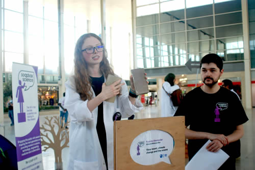 Young female scientist gives a talk in the middle of a shopping centre