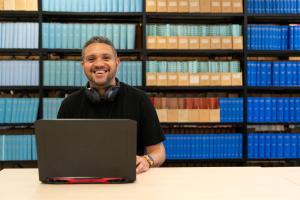 Student studying in library with laptop smiling