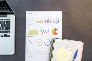 Top-down view of a desk with charts, a laptop, and notebooks.
