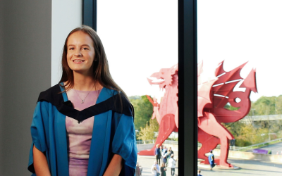 graduate in front of a dragon statue