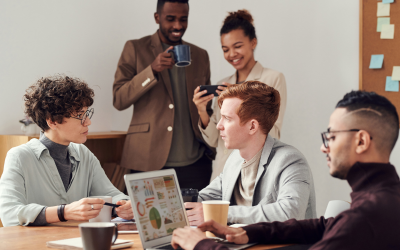 People meeting at a table and someone working on a laptop
