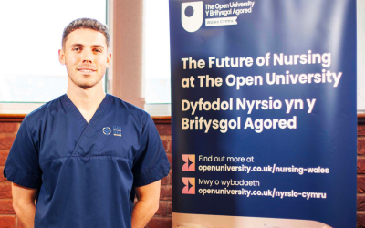 Nurse stood next to an OU banner