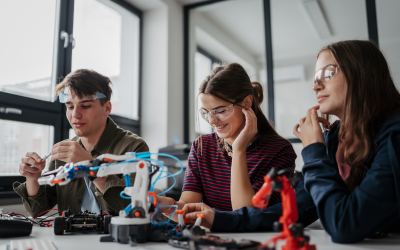 Students wearing protective eyewear working with robotic arms