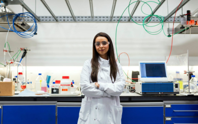 A student in a laboratory with safety goggles and a white labcoat