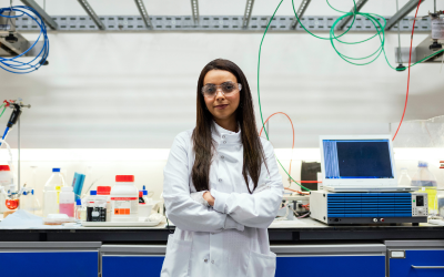 A student in a laboratory with safety goggles and a white labcoat