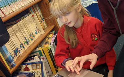 A school child is supported to look at asteroid data on a laptop