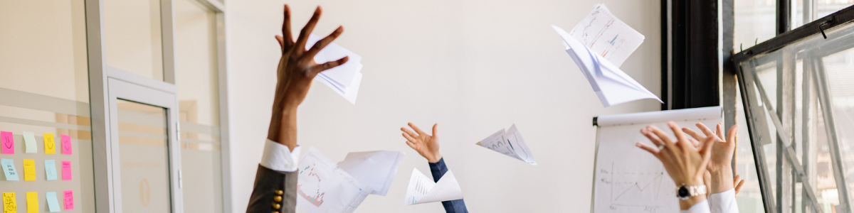 Group of people in a meeting room throwing papers in the air